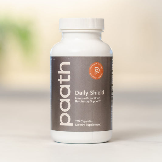 Supplement bottle labeled 'Daily Shield' by 'paath' on a blurred background