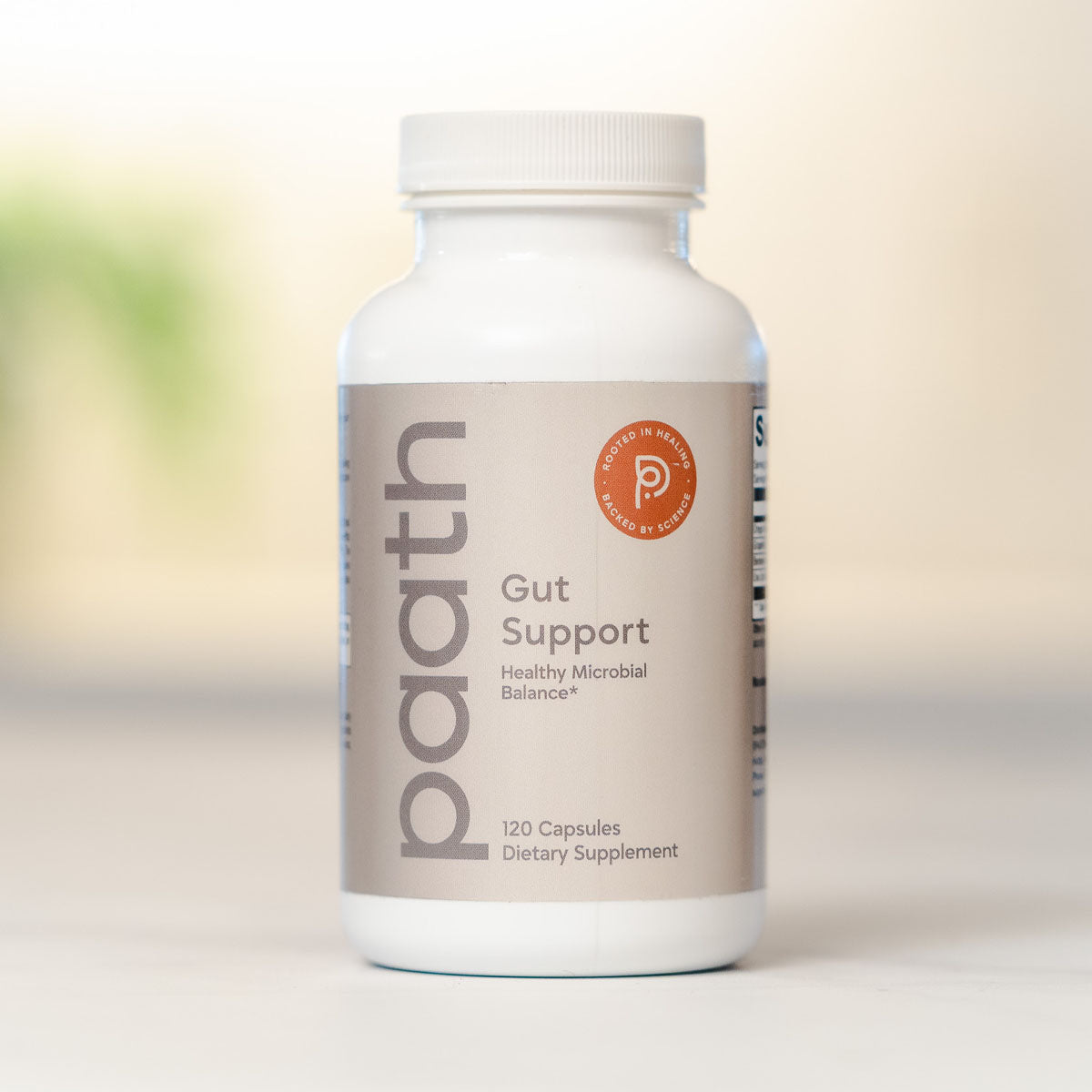 Supplement bottle labeled 'paath Gut Support' on a blurred background