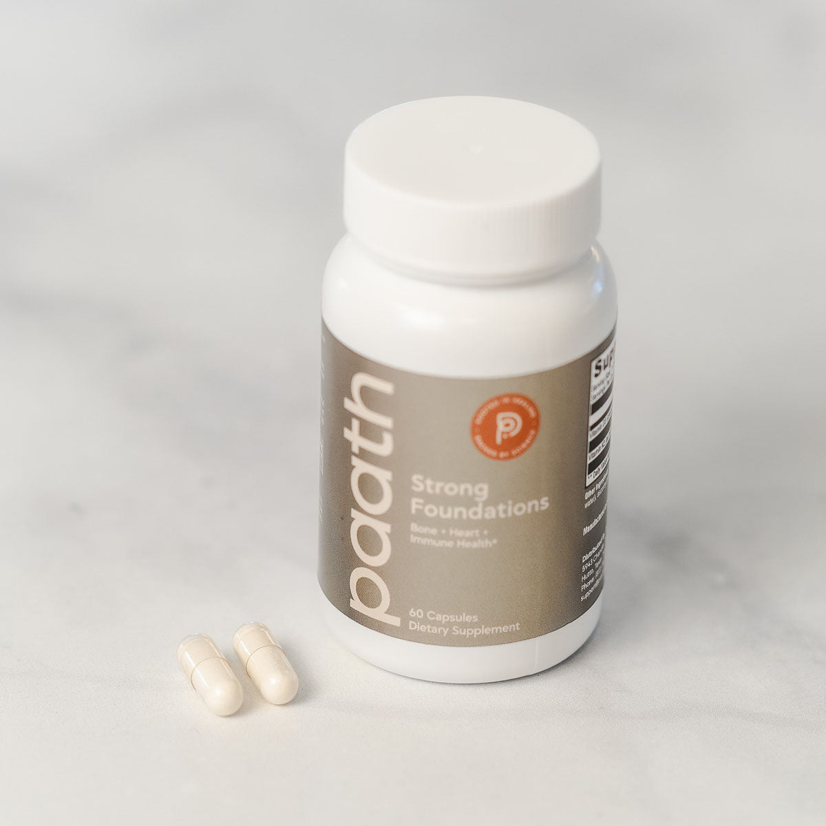 Supplement bottle labeled 'paath' with capsules on a light gray background