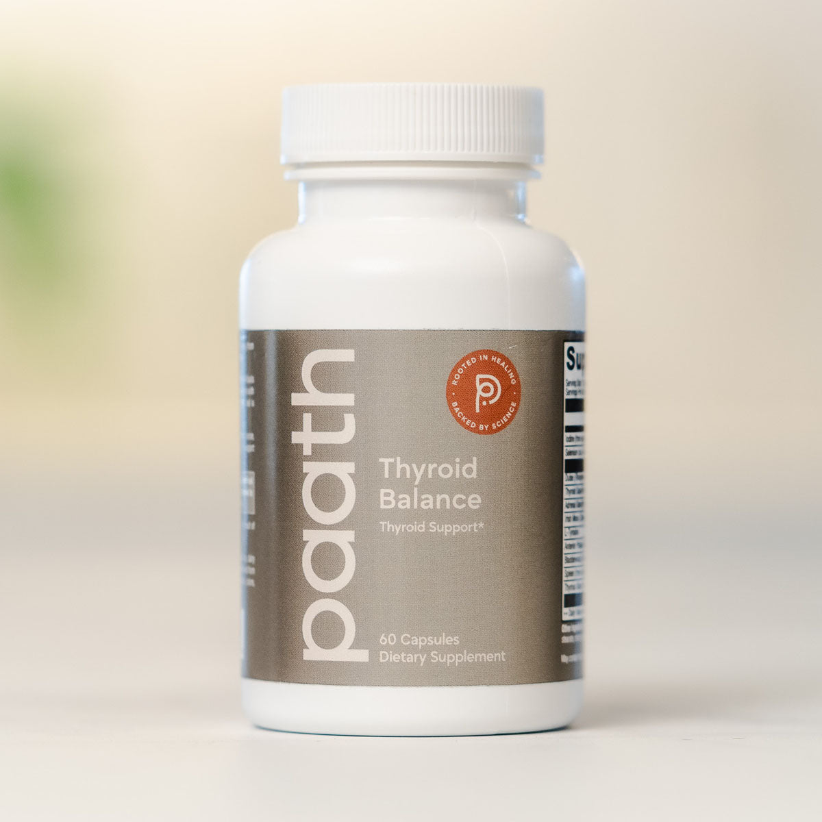 Supplement bottle labeled 'paath Thyroid Balance' on a light background